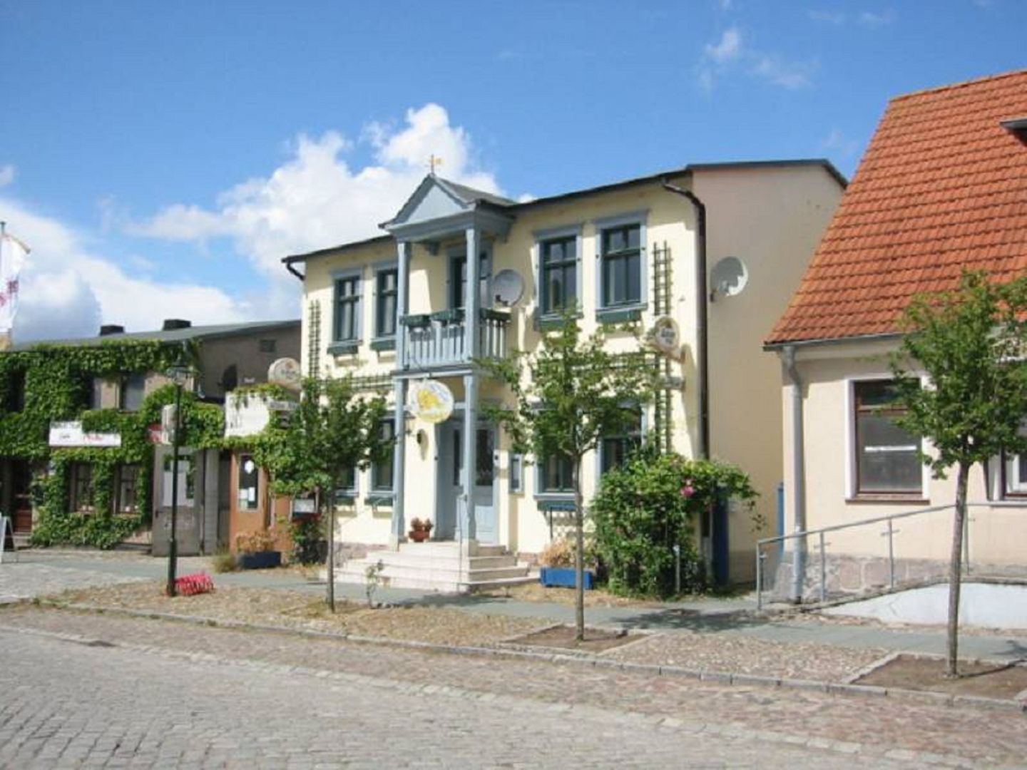 A two-story building with a balcony, a signboard, and a red-tiled roof.