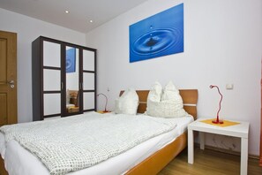 A bedroom with a bed, a nightstand, a wardrobe, and a wall-mounted painting.