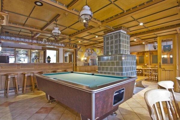 A pool table in a room with wooden ceiling beams, a bar area, and a mural on the wall. - F-1065 Brunnenaue - Brunnenaue Group Home F-1065 (Sagard)