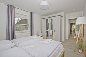 A bedroom with two beds, a wardrobe, a lamp, and a potted plant. - Modern vacation apartment with private terrace - Haus Inselwind FeWo MEERglück - (Gager)