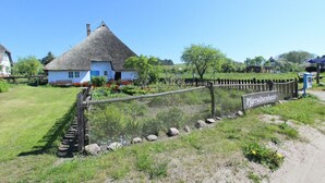 Une maison traditionnelle à toit de chaume, avec une pancarte indiquant « Pfarrwitwenhaus » devant l’entrée.