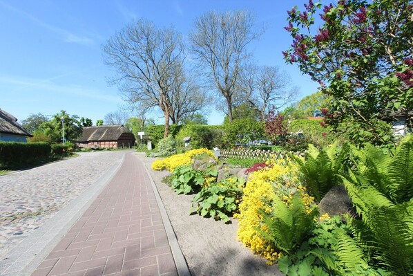 A cobblestone street leading to a traditional building with a thatched roof.