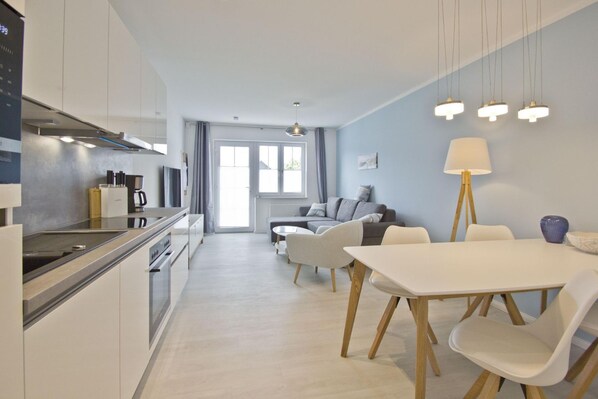 A modern kitchen with a dining area, a sofa, and a lamp.