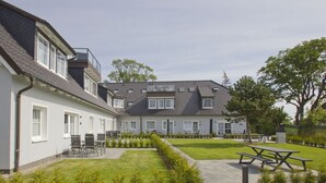 Un immeuble résidentiel doté d’une cour intérieure, d’un espace extérieur aménagé pour s’asseoir et d’une pelouse bien entretenue.