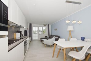 Une cuisine moderne avec des meubles blancs et un coin repas comprenant une table et des chaises blanches.
