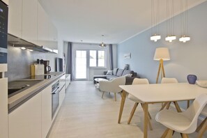A modern kitchen with a dining area, a sofa, and a lamp. - Modern vacation apartment with private terrace - Haus Inselwind FeWo MEERsand - House (Gager)