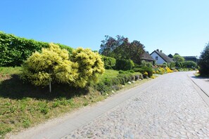 A cobblestone street lined with lush greenery and traditional houses. - Free use of the AHOI adventure pool and sauna - Inselwind FeWo MEERbodden - (Gager)
