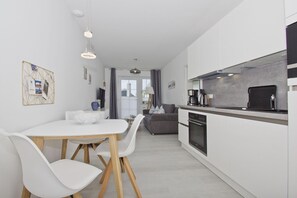 Una cocina moderna con horno integrado y comedor con mesa y sillas blancas.