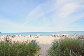 Une plage avec des cabanes de plage numérotées où les gens se détendent.
