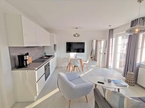 Una cocina moderna con armarios blancos, una cafetera negra y un televisor de pantalla plana montado en la pared.