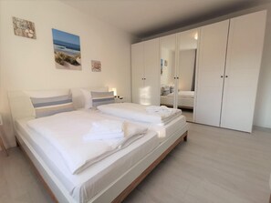 Un dormitorio moderno con una cama grande, un armario y una mesita de noche.