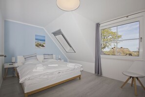 A bedroom with a bed, a bedside table, a nightstand, a window with curtains, and a view of the outside.