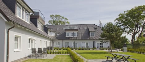 Un edificio residencial con patio, mobiliario exterior y un césped cuidado.