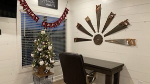 Una habitación con un árbol de Navidad, un escritorio y una decoración de hojas de sierra.