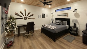 Un dormitorio con cama, escritorio, silla y un árbol de Navidad.