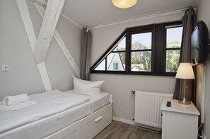 Un dormitorio con cama, ventana, radiador y lámpara.