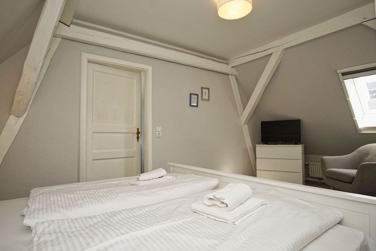 A bedroom with two beds, a door, a dresser, a chair, and a television.
