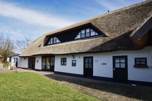 A traditional building with a thatched roof, white walls, and black-framed windows.