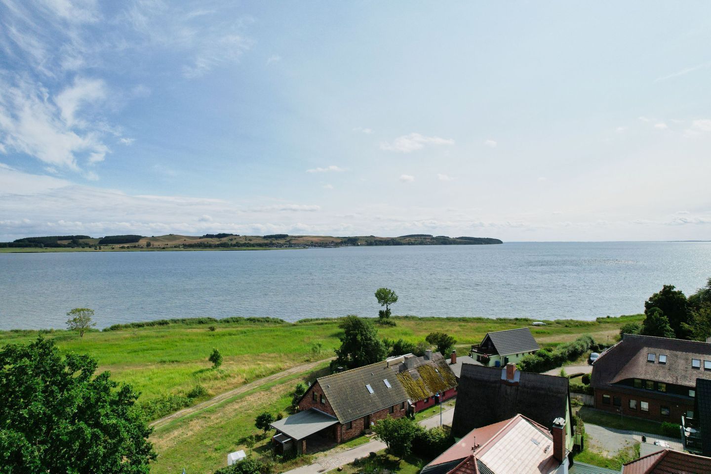 Une zone résidentielle côtière comprenant des maisons, un champ d’herbe et une étendue d’eau.