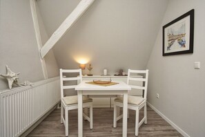 A small, white-framed dining area with a table and chairs, a starfish decoration, a framed picture on the wall, and a radiator on the floor. - Close to the sea, quiet location, access to the pool and sauna - Haus Büdnerstube FeWo 5 (Middelhagen)