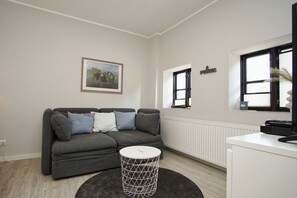 A modern living room with a grey sofa, a round coffee table, and a radiator.