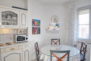 A kitchen with white cabinets, a microwave, a dining table with chairs, and a hanging light fixture.