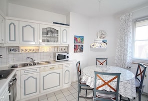 A kitchen with white cabinets, a microwave, a sink, and a dining table with chairs.