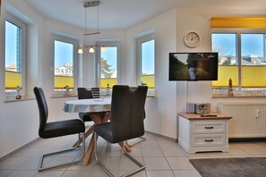 Una cocina moderna con comedor, ventanas amplias, un televisor de pantalla plana y un mueble pequeño con radio.