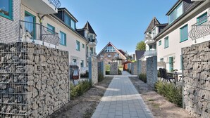 A residential street with stone walls, a paved walkway, and houses with balconies. - Domizil Strandburg Appartement 5 - Domizil Strandburg (Timmendorfer Strand)