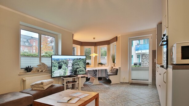 A compact living space with a television, sofa, coffee table, and a small dining area. - Domizil Strandburg Appartement 5 - Domizil Strandburg (Timmendorfer Strand)