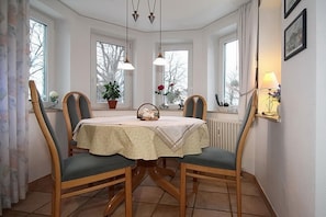 Una sala da pranzo con un tavolo rotondo, quattro sedie e un lampadario.