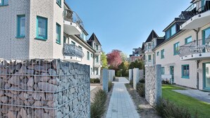 Un barrio residencial con edificios modernos de ladrillo, un sendero pavimentado y un muro de piedra.