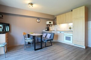 A compact kitchen with a dining area, a microwave, and a clock on the wall. - Domizil Strandburg Appartement 08 - Domizil Strandburg (Timmendorfer Strand)