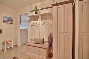 Une pièce comprenant un banc en bois, une petite table et une étagère fixée au mur, sur laquelle se trouve une plante.