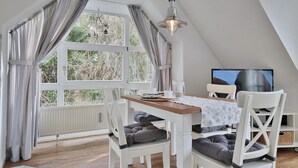 A cozy dining area with a table, chairs, and a television. - Am Elchgrund Apartment 12 - Im Brook 36-38 (Timmendorfer Strand)