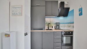 Een moderne keuken met grijze kastjes, een ingebouwde oven en een koffiezetapparaat op het aanrecht.