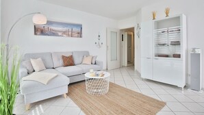 Een moderne woonkamer met een grijze bank, een ronde salontafel en een witte kast met glazen deuren.