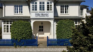 Villa María, un edificio de dos pisos con fachada simétrica, ventanas amplias y una entrada central.