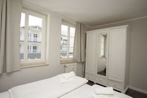 Une chambre à coucher avec un lit, une armoire et une fenêtre avec des rideaux.
