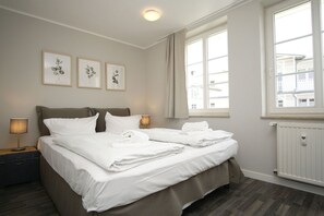 A hotel room with a bed, bedside lamps, a window, and framed artwork on the wall. - Vacation apartment in spa style with conservatory - Villa Maria FeWo Marianne 35 - (Göhren)