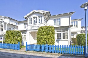 A white building with a sign reading "Villa Maria" and a blue picket fence in front. - Bathroom-style vacation apartment with conservatory - Villa Maria FeWo Maja 36 - Villa (Göhren)