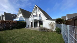 Ein zweistöckiges Haus mit Balkon, Veranda und umzäunter Garten.