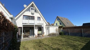 A two-story house with a balcony, a patio with outdoor furniture, and a fenced yard. - Vacation apartment in a quiet location and with balcony - Ferienhaus Solamar FeWo OG - (Breege)