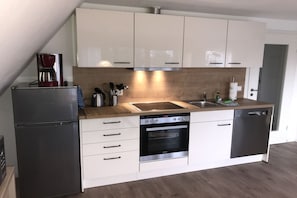 A modern kitchen with white cabinets, a stainless steel refrigerator, a built-in oven, and a dishwasher. - Vacation apartment in a quiet location with a balcony - Ferienhaus Solamar FeWo OG - (Breege)