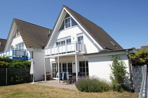 A two-story house with a balcony, a covered patio, and a fenced yard.