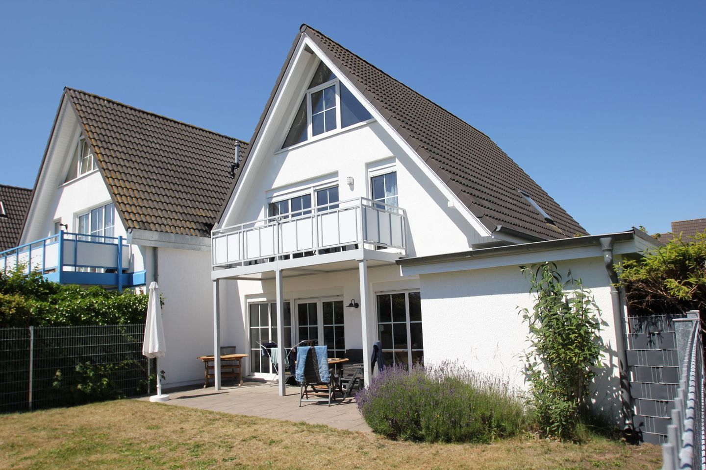 A two-story house with a balcony, a covered patio, and a fenced yard.