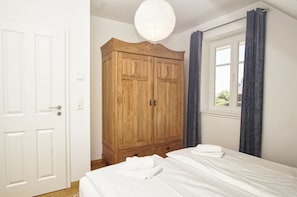 A bedroom with a bed, a wardrobe, a window with curtains, and a door.