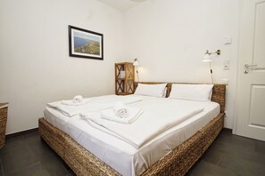 A neatly made double bed with white linens, a framed landscape photo on the wall, and a bedside table with a lamp. - Vacation home Rohrweihe - waterfront vacation home with sea view in a quiet location - (Gager)