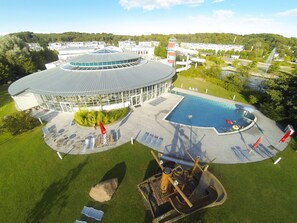 Ein kreisförmiges Gebäude mit Schwimmbad, Liegestühlen und einer Wasserrutsche.