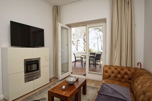 A living room with a flat-screen TV, built-in oven, and a sofa. - Villa Seeadler - Die Ferienwohnung in der Villa Seeadler (Binz)